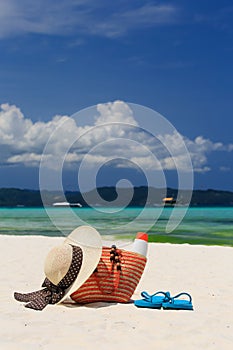 Hat, bag, sun glasses and flip flops on tropical beach