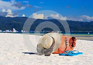 Hat, bag, sun glasses and flip flops on tropical beach