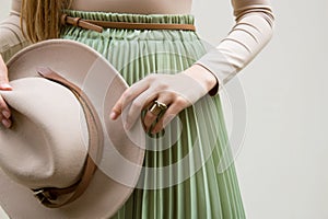 Hat, beige blouse and turqoise pleats skirt on light street backgraund. photo
