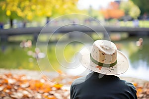 hat by campus pond, ducks nearby, student watching