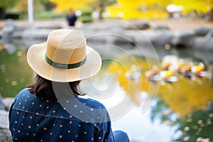 hat by campus pond, ducks nearby, student watching