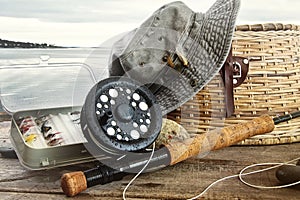 Hat and fly fishing gear on table near the water