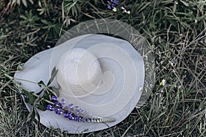 The hat lies on the grass in a field of blooming lupins.