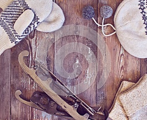 Hat, mittens and vintage skates on a wooden background.