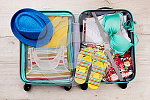 Hat and slippers on packed suitcase.