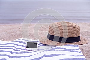 Hat and smart phone on the beach.