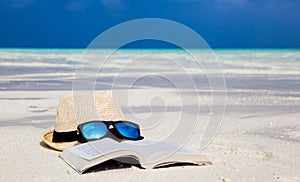 Hat, sunglasses and a book on the beach