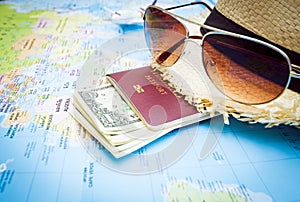 Hat, sunglasses, passport, money and aircraft on the world map