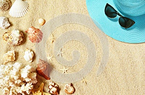 Hat and sunglasses on the sandy beach with seashells. Summer background