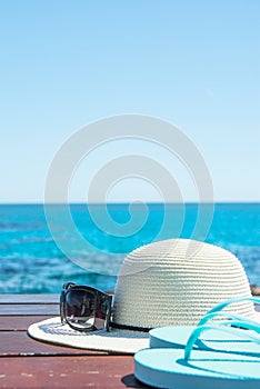 Hat Sunglasses Slippers on Blue Sky and Turquoise Sea Background. Summer Vacation Travel Relaxation. Idyllic Seascape View