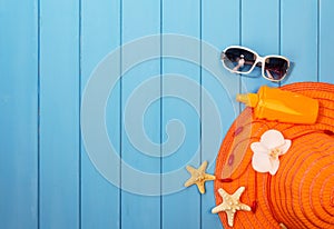 Hat, sunglasses and suntan lotion on wood background colored.