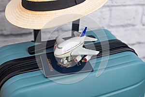 A hat with a US passport lies on a suitcase with a US flag. Travel concept