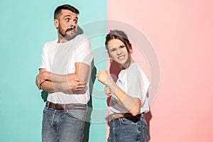 The young emotional angry woman on pink studio background