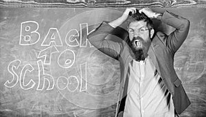 Hate school. Teacher or educator stands near chalkboard with inscription back to school. Teacher unhappy shouting