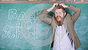 Hate school. Teacher or educator stands near chalkboard with inscription back to school. Teacher unhappy shouting