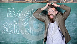 Hate school. Teacher or educator stands near chalkboard with inscription back to school. Teacher unhappy shouting