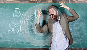 Hate school. Teacher goes mad about schooling. Teacher or educator stands near chalkboard with inscription back to