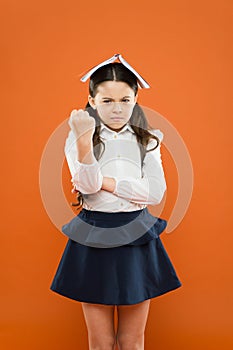 She hates reading. Angry small child tired of reading book on orange background. Unhappy little schoolgirl having