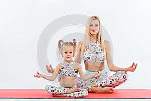 Hatha yoga fitness . Young mother and daughter exercise together indoors. Family look.