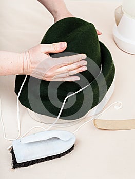 Hatter fixes a felt hood on dummy for shaping