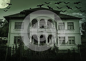 Haunted house with dark horror atmosphere and full moon. Creepy old mansion at night. Spooky scene like in frightening movies. Sty