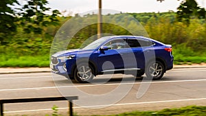 Haval F7x five door SUV is driving at high speed on country road. Overspeed out of city concept. Blue crossover car in motion