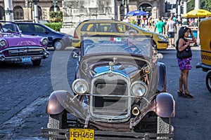 Havana / Cuba - 07/2018: Old and rusty cars of fifties on Havana streets. Brown ones rented on the front view, the pink one on the