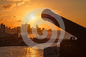 Havana at sunset with the silhouette of an old cannon on the foreground