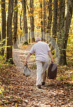 Always have bag ready to go. Elderly person carry travel bag. Old man travel with retro bag. Living vagabond life