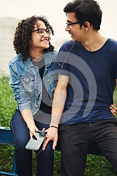 We have cool conversations about the music we love. a teenage couple listening to music together outdoors.