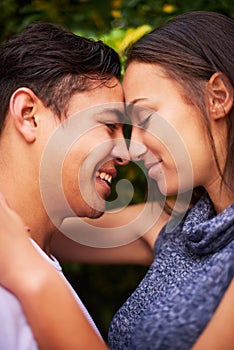 They only have eyes for each other. Closeup shot of a smiling young couple embracing face to face outside.