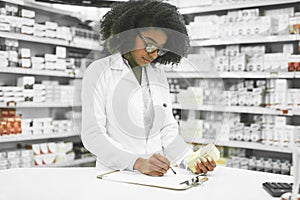 We have a few scheduled pickups today. a focused young female pharmacist making notes while reading the label of a