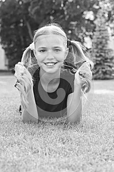 Have fun. Girl cute kid laying green grass. Healthy emotional happy kid relaxing outdoors. What makes child happy. Girl