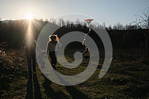 Have fun spending time with two children outdoors in nature. Rear view. Young parents with son and daughter run across field at