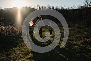 Have fun spending time with two children outdoors in nature. Young Caucasian parents with their son and daughter run across field