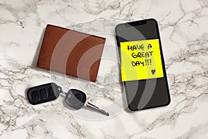 Have a great day romantic and sweet handwritten note on yellow posit stick to mobile phone next to car key and leather wallet in photo