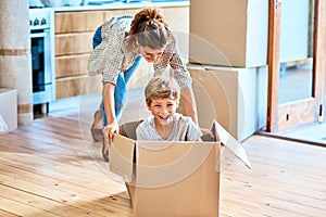 We have liftoff. Shot of a cheerful young woman pushing her son around in a box imagining its a car inside at home