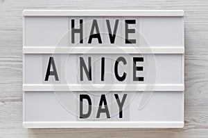 `Have a nice day` words on a lightbox on a white wooden background, top view. Overhead, from above, flat lay. Close-up