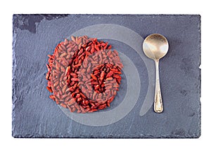 Have a power snack. Studio shot of a pile of goji berries in the shape of a circle with a spoon next to it.