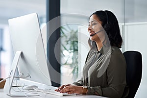 We have a team of experts waiting for your call. a woman wearing a headset while looking at her desktop in a call centre