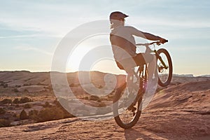 Have two wheels, will travel. Full length shot of a young male athlete popping a wheelie while mountain biking in the