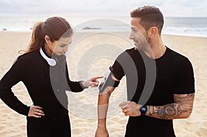 Have you got your running playlist ready. Sporty young man and woman preparing for working out together on the beach