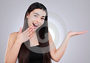 Have you heard about this too. Studio shot of an attractive young woman looking surprised while pointing to copyspace