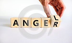 Having anger or being an angel. Businessman turns a wooden cube and changes the word anger to angel. Beautiful white background.