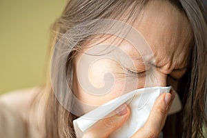 Having a cold or corona virus flu symptoms. Young woman with a an allergy sneezing into her handkerchief.
