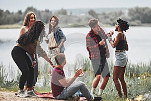 Having conversation with each other. Group of people have picnic on the beach. Friends have fun at weekend time