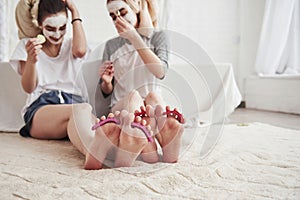 Having conversation. Pedicure and painted leg nails. Conception of skin care by using white mask and cucumbers on the