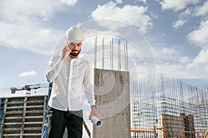 Having conversation by the phone. Man in uniform is working on the construction site