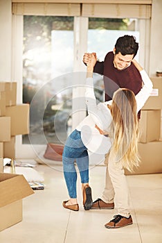 Having the first dance in their new home. Full length shot of an affectionate young couple dancing while moving into a