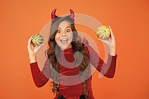 Having fun. Decorations for holidays. Playful imp. Girl with horns play with pumpkins. Happy holidays. Cute child
